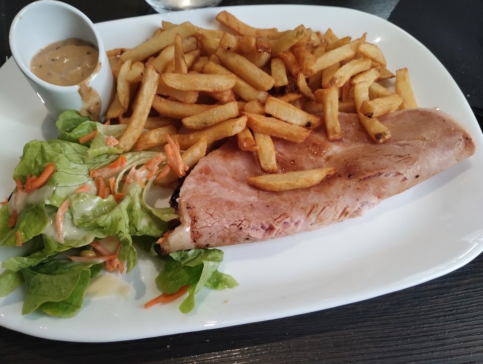 Table de restaurant avec plats régionaux et verres de bière.